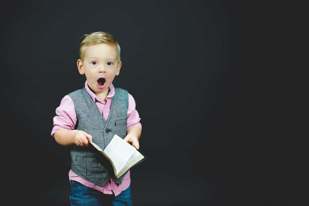 A photo of an astonished kid with a book, knowing about Islam.